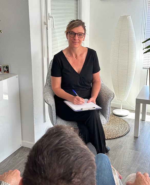Barbara Masson en consultation, assise face à un client, dans un intérieur lumineux et apaisé